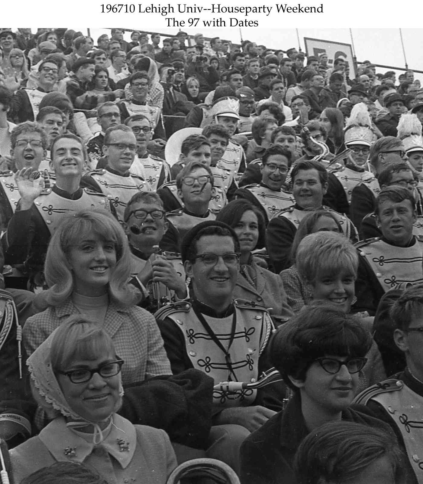 Bandmembers and their dates sit next to each other, smiling at the camera and watching the game