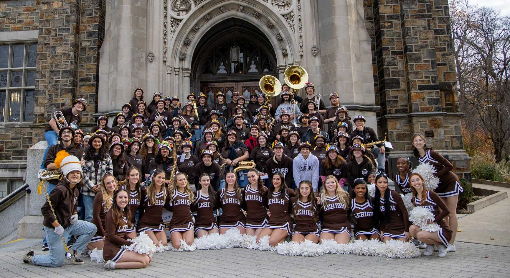 The Marching 97 and cheerleaders smiling in front of Linderman Library