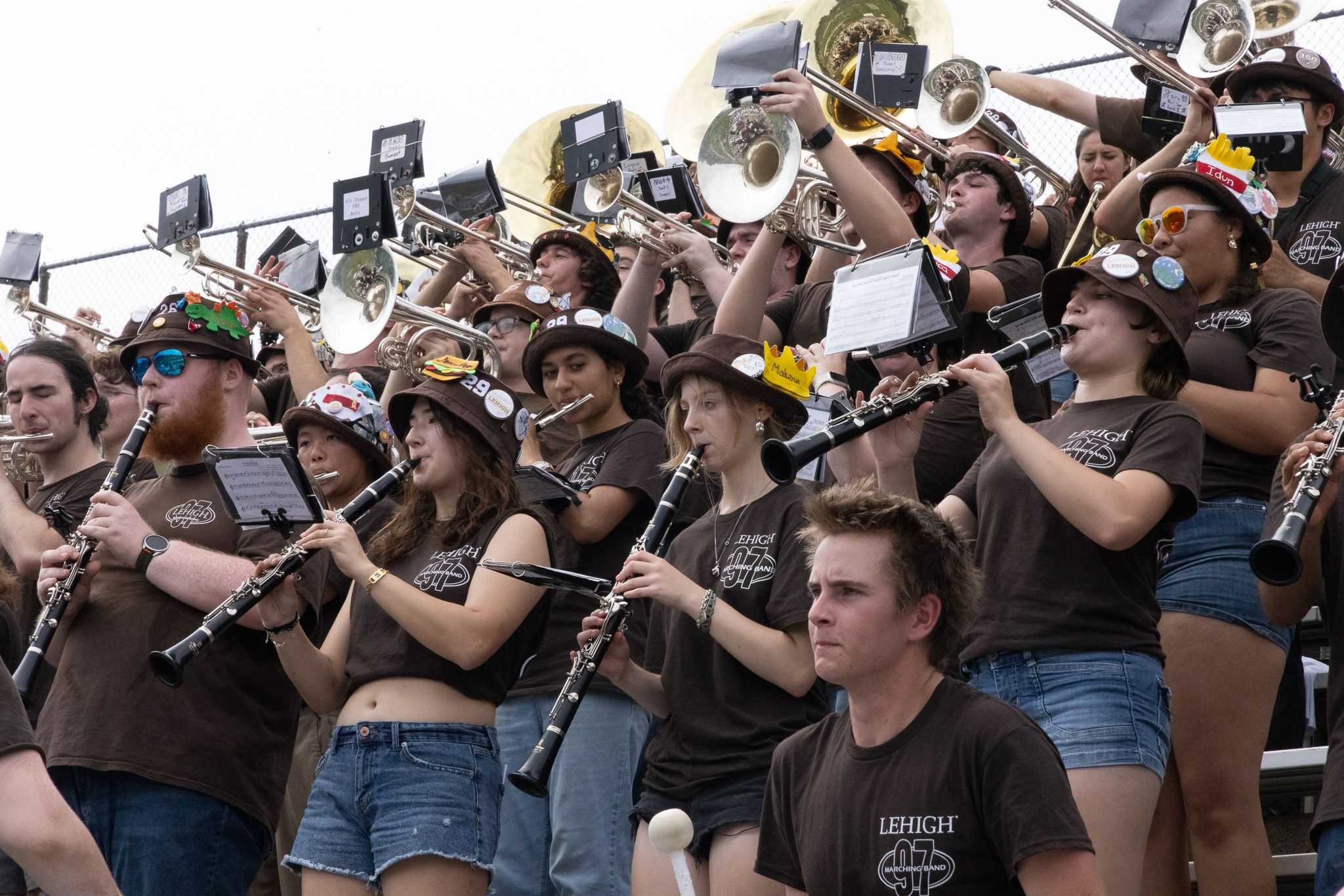 The band playing in the stands with clarinets in front, followed by mellophones, trumpets, and trombones